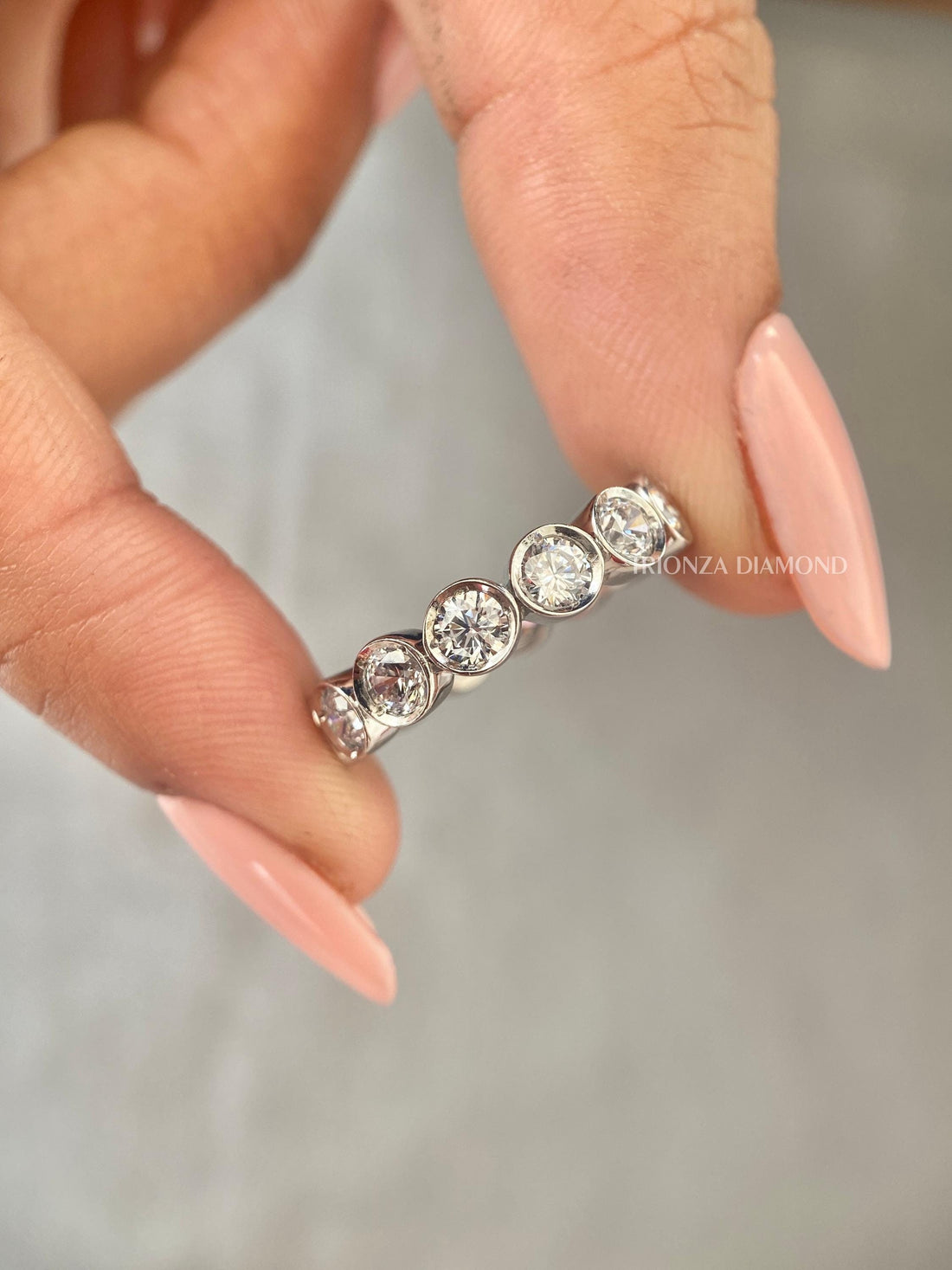 Bezel set round lab grown diamond eternity wedding band crafted in yellow gold for stacking