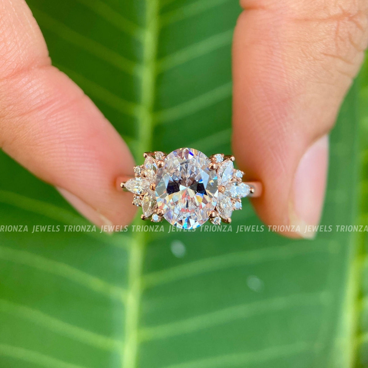 Oval cut moissanite engagement ring featuring marquise and round side stones in a cluster design