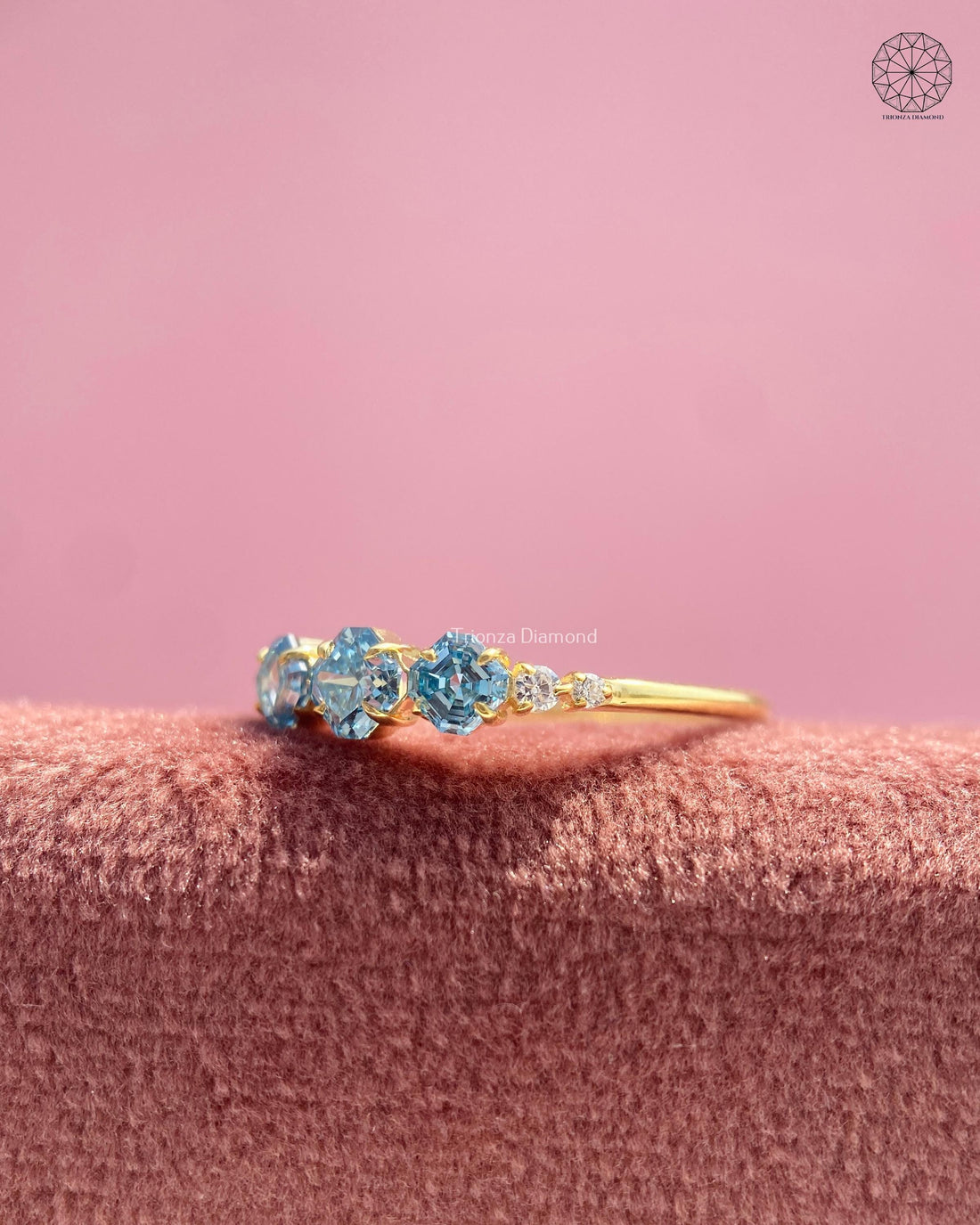 Three stone Asscher cut blue diamond engagement ring displayed to show its trilogy setting