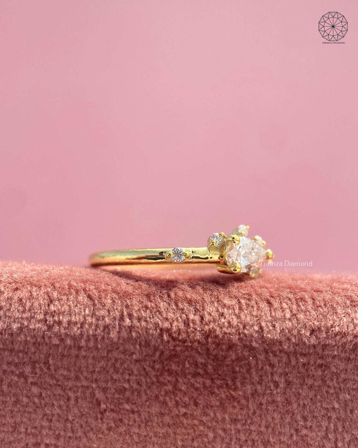 Close-up of the dainty prong set teardrop diamond with round accent stones