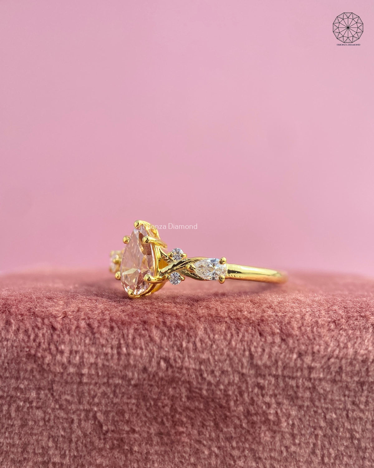Close-up of the three stone pear diamond ring showing the botanical leaf vine details