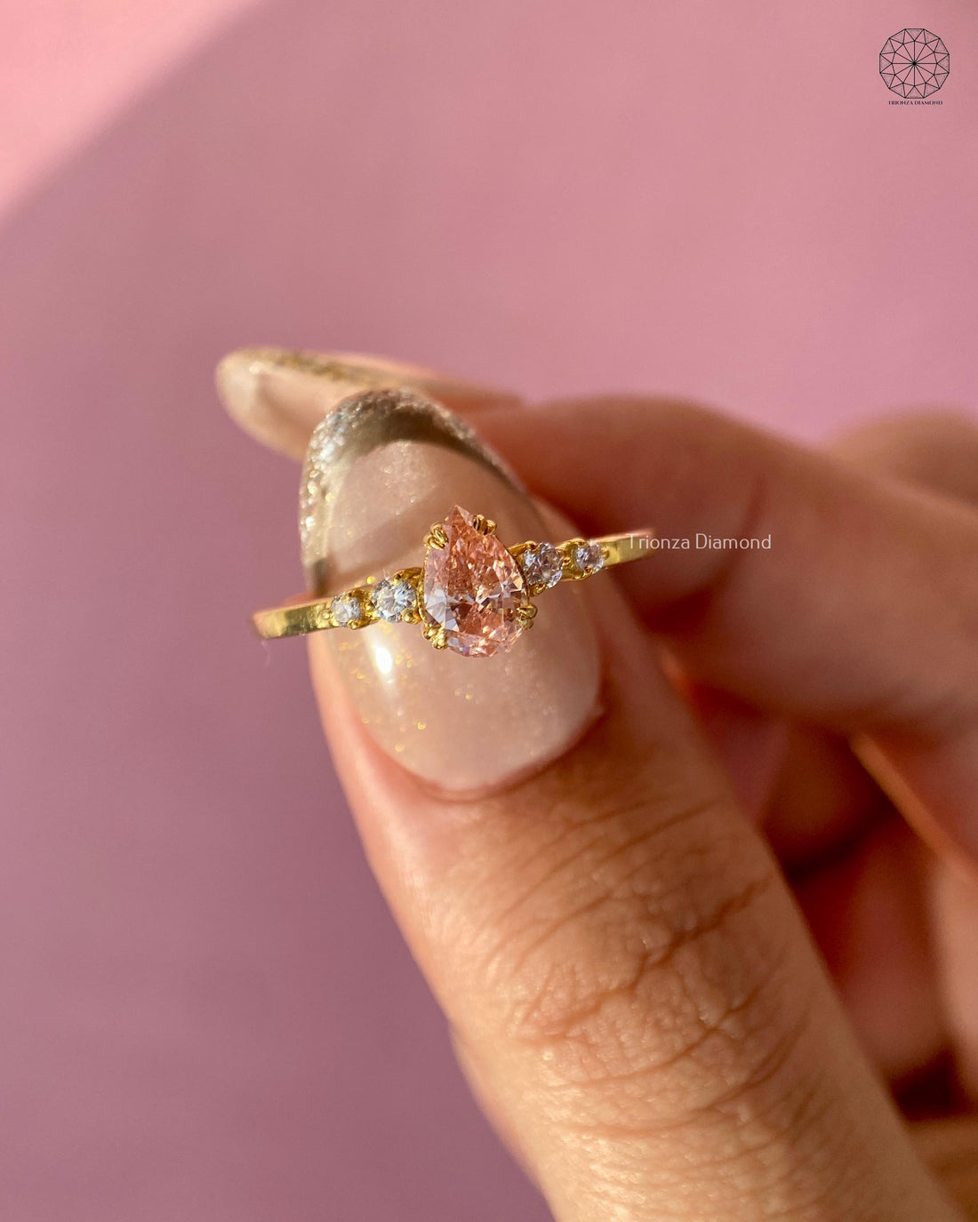 Pink pear lab grown diamond engagement ring set in yellow gold with five stone accents