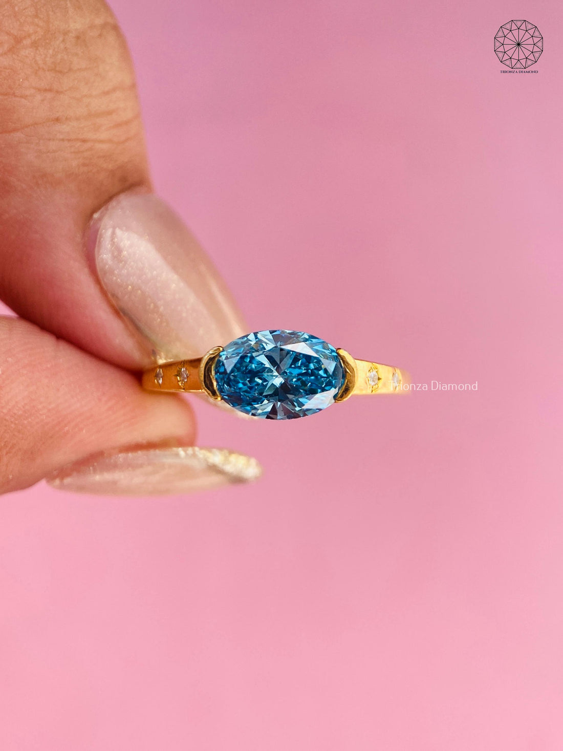 Oval cut blue diamond solitaire ring featuring a half-bezel setting with star accent details