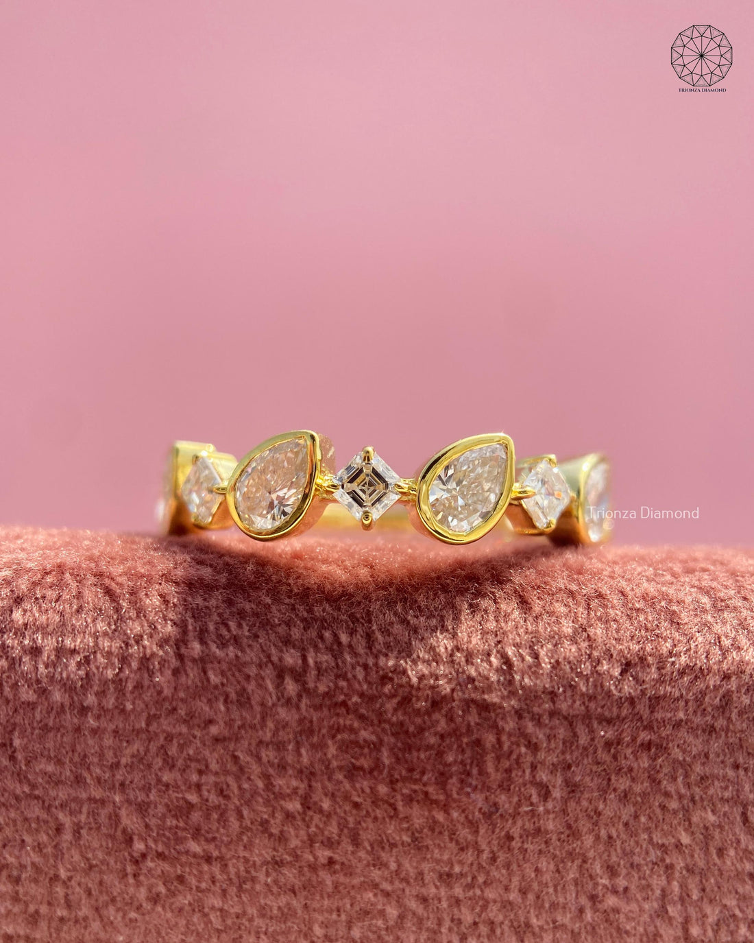 Yellow gold wedding band featuring a geometric cluster of bezel set pear and Asscher cut diamonds