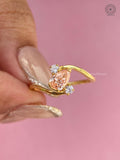 14K yellow gold ring with round side diamonds flanking the orange pear shaped center stone