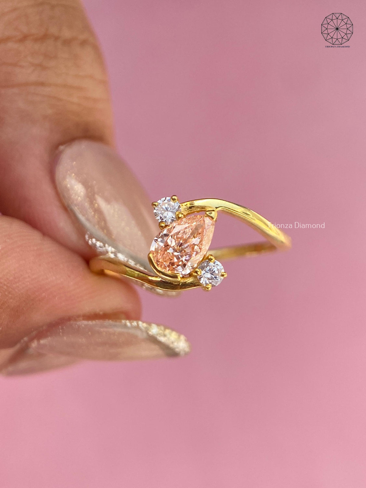 14K yellow gold ring with round side diamonds flanking the orange pear shaped center stone