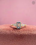 Emerald cut lab grown diamond ring featuring blue color and pear cut side stones in yellow gold