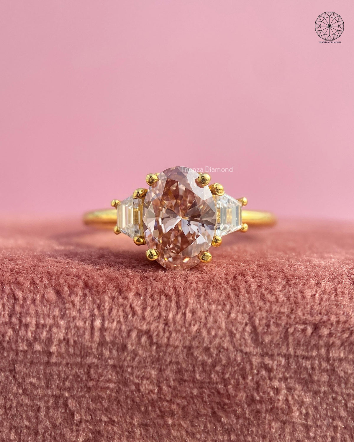 Three stone oval engagement ring featuring a champagne diamond set in yellow gold