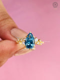 Pear cut blue lab grown diamond ring displayed to show its three stone cluster design