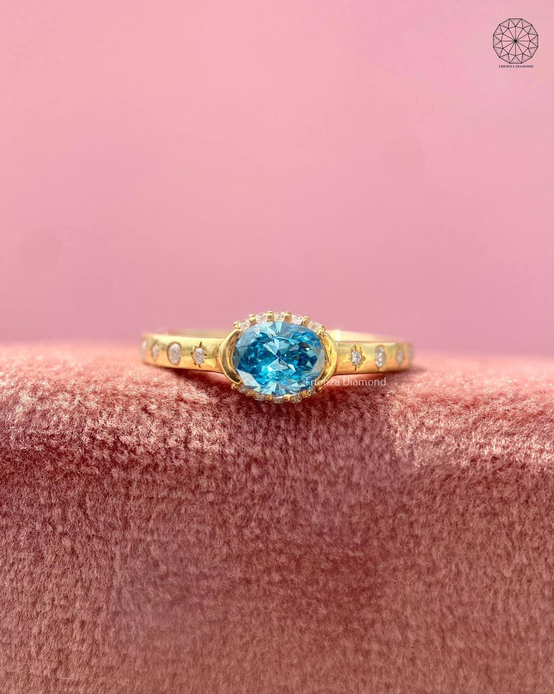 Oval blue gemstone engagement ring with a lab grown diamond halo in yellow gold