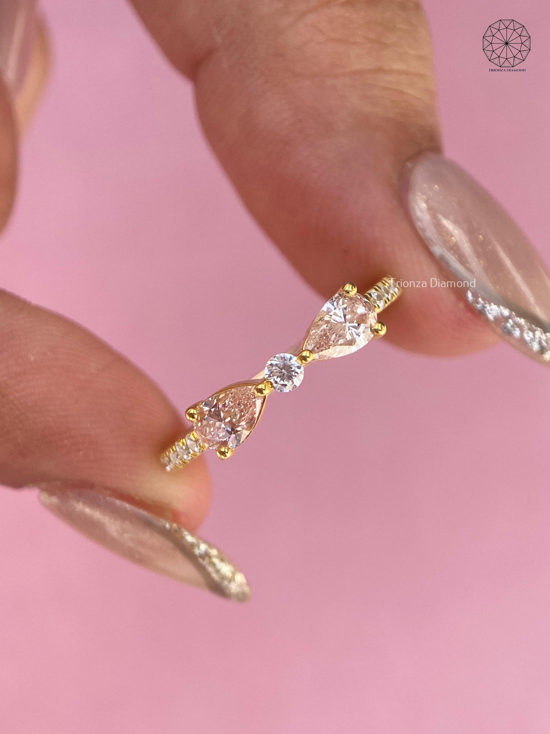 Pear cut lab grown diamond ring with round side stones in a yellow gold trellis setting