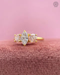 Marquise diamond ring displayed to show the yellow gold band and pink round accent stones