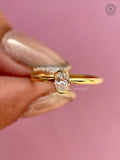 Side view of the oval diamond ring highlighting its sleek bezel profile