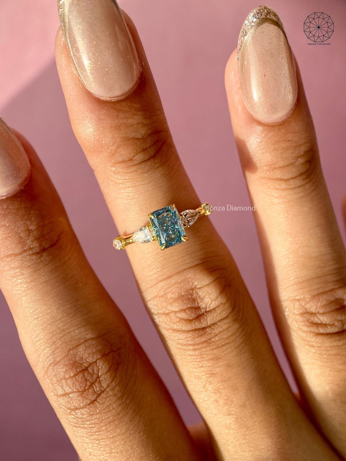 Statement engagement ring displayed to highlight the teal blue radiant center stone