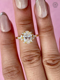 Statement bridal ring featuring an oval diamond with floral accents in yellow gold