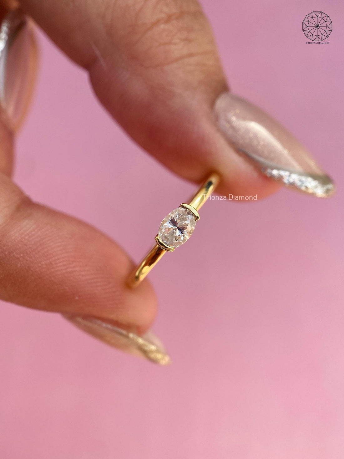 East west oval diamond solitaire ring featuring a half bezel setting on a polished gold band