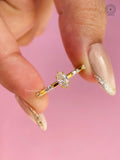 Marquise cut lab grown diamond ring featuring a dainty yellow gold band with round accent clusters