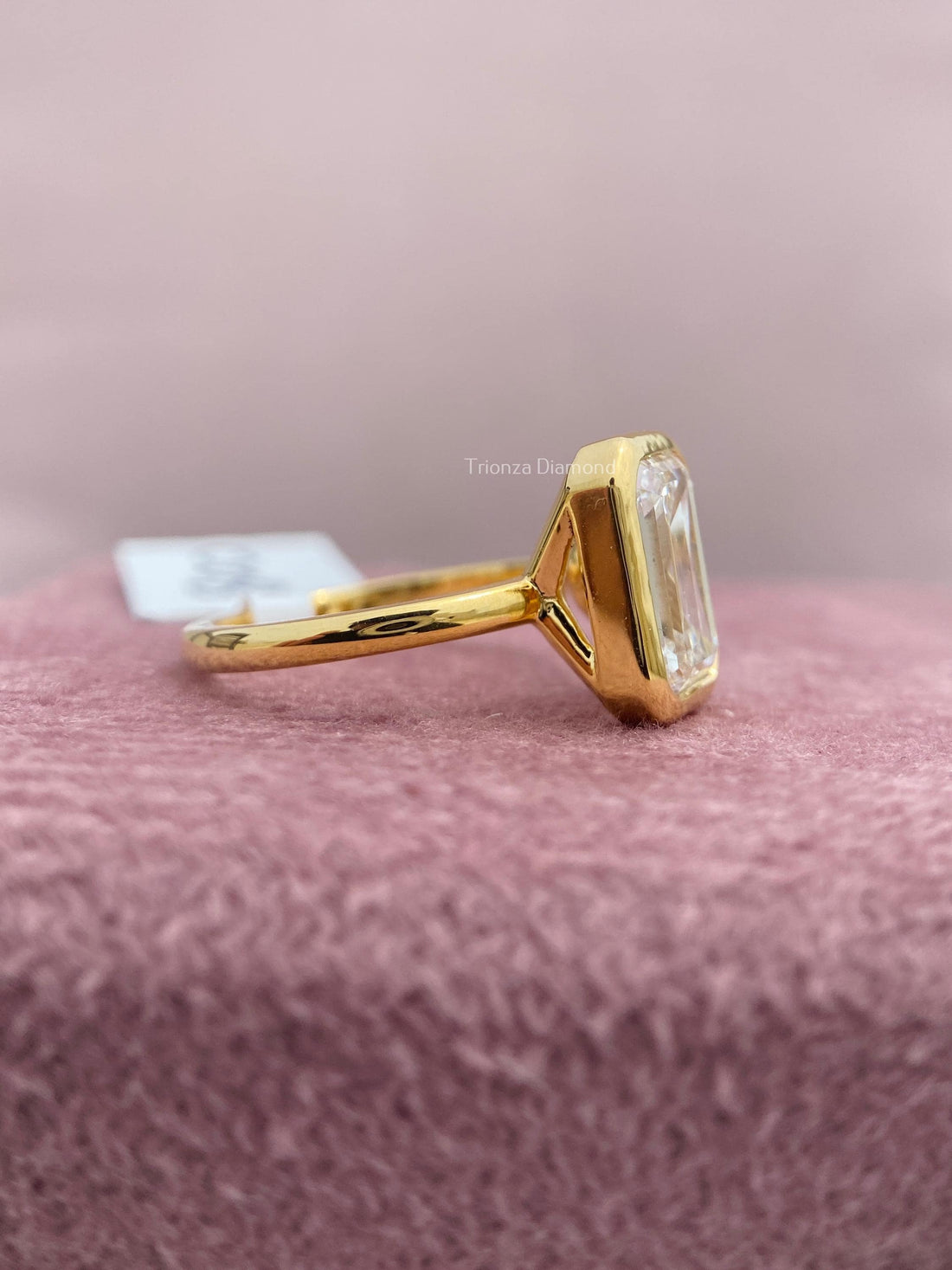 Emerald cut lab grown diamond engagement ring showcasing a bezel set solitaire design in 14k gold