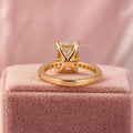 Round cut diamond accents surrounding the radiant center stone in a hidden halo design