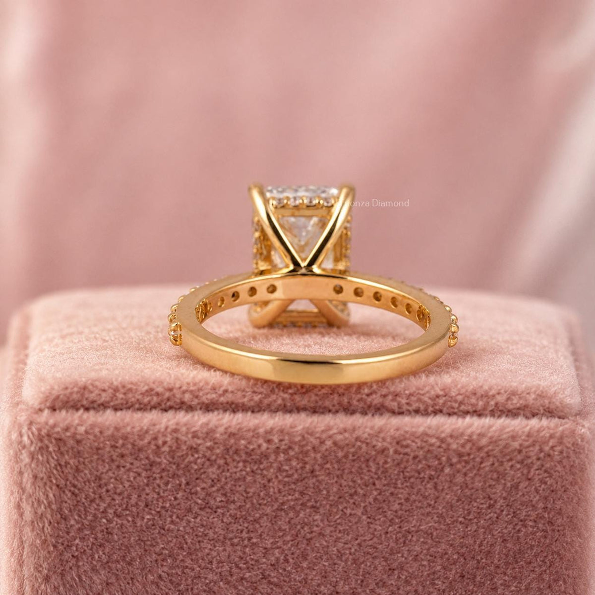 Round cut diamond accents surrounding the radiant center stone in a hidden halo design