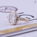 Three stone trilogy ring featuring a 3 carat cushion cut center diamond in 14k yellow gold
