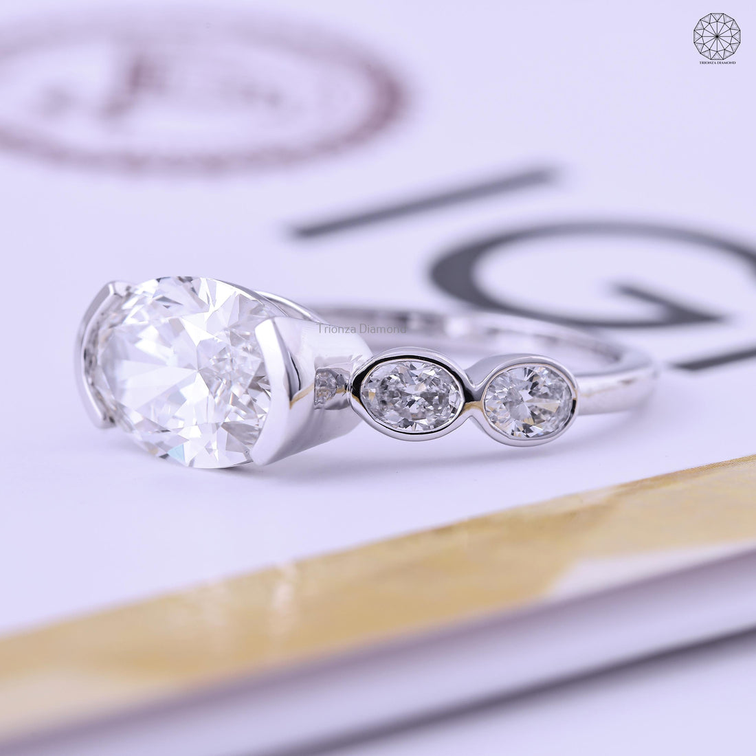 East West oval lab grown diamond engagement ring featuring a semi bezel gold setting