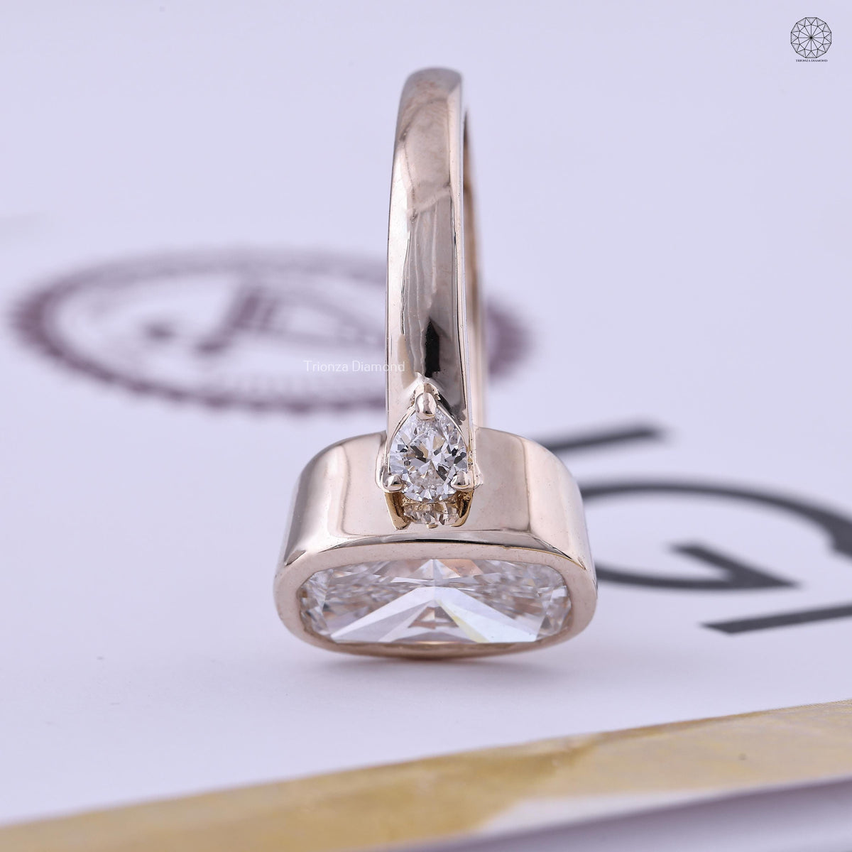 Pear cut side stones flanking the elongated cushion center diamond in this three stone ring