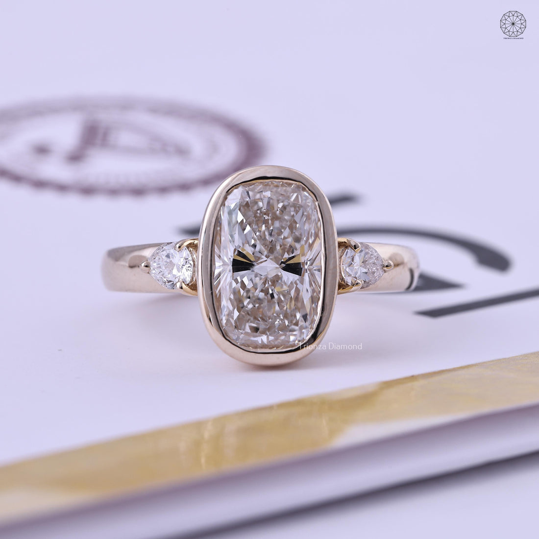 Elongated cushion cut lab grown diamond ring with bezel setting and pear shaped side stones