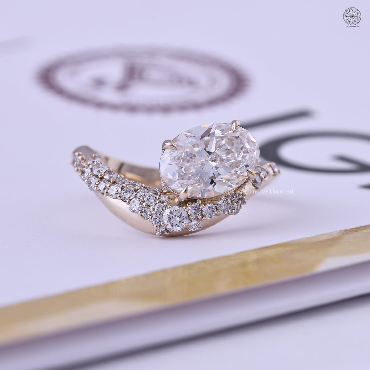 Oval lab grown diamond engagement ring with a curved gold band and cluster diamond accents