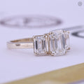 Close-up of the emerald cut center stone flanked by two matching emerald side stones
