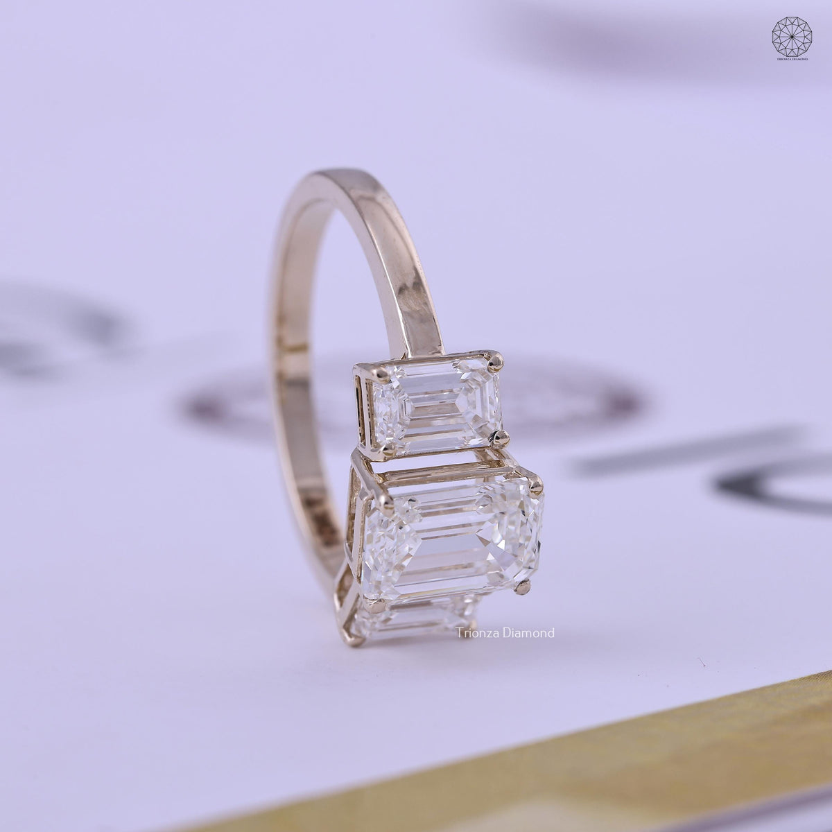 Side view of the three stone ring displaying the prong set emerald cut diamonds